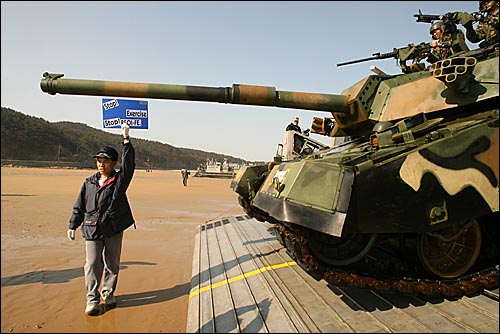 충남 태안 만리포 해수욕장 해변에 공기부양정에 실려 상륙하려는 탱크를 시위자가 가로막고 있다. 